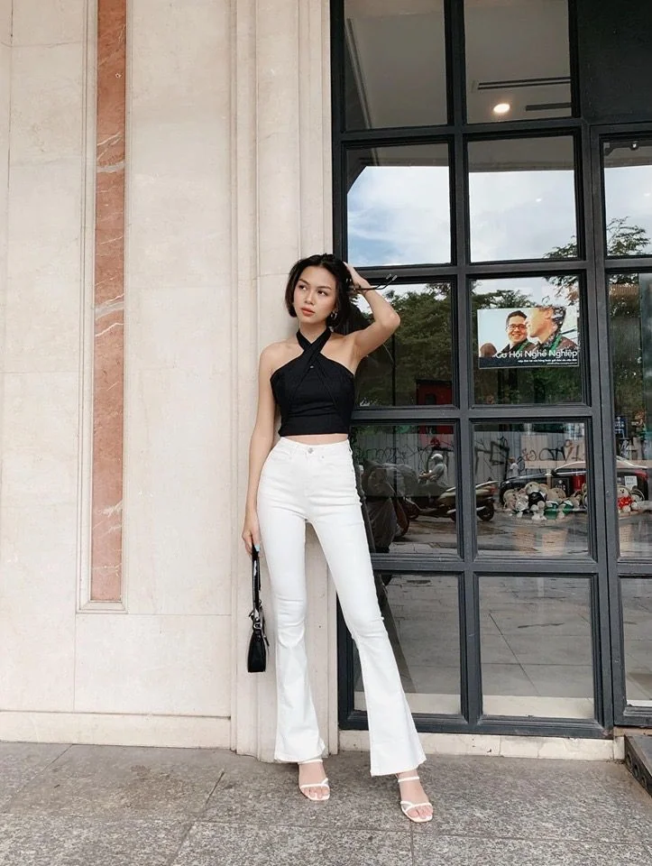 Белые брюки-клеш в вечернем образе Белые джинсы-клёш с чёрным топом-халтером и босоножками на каблуке